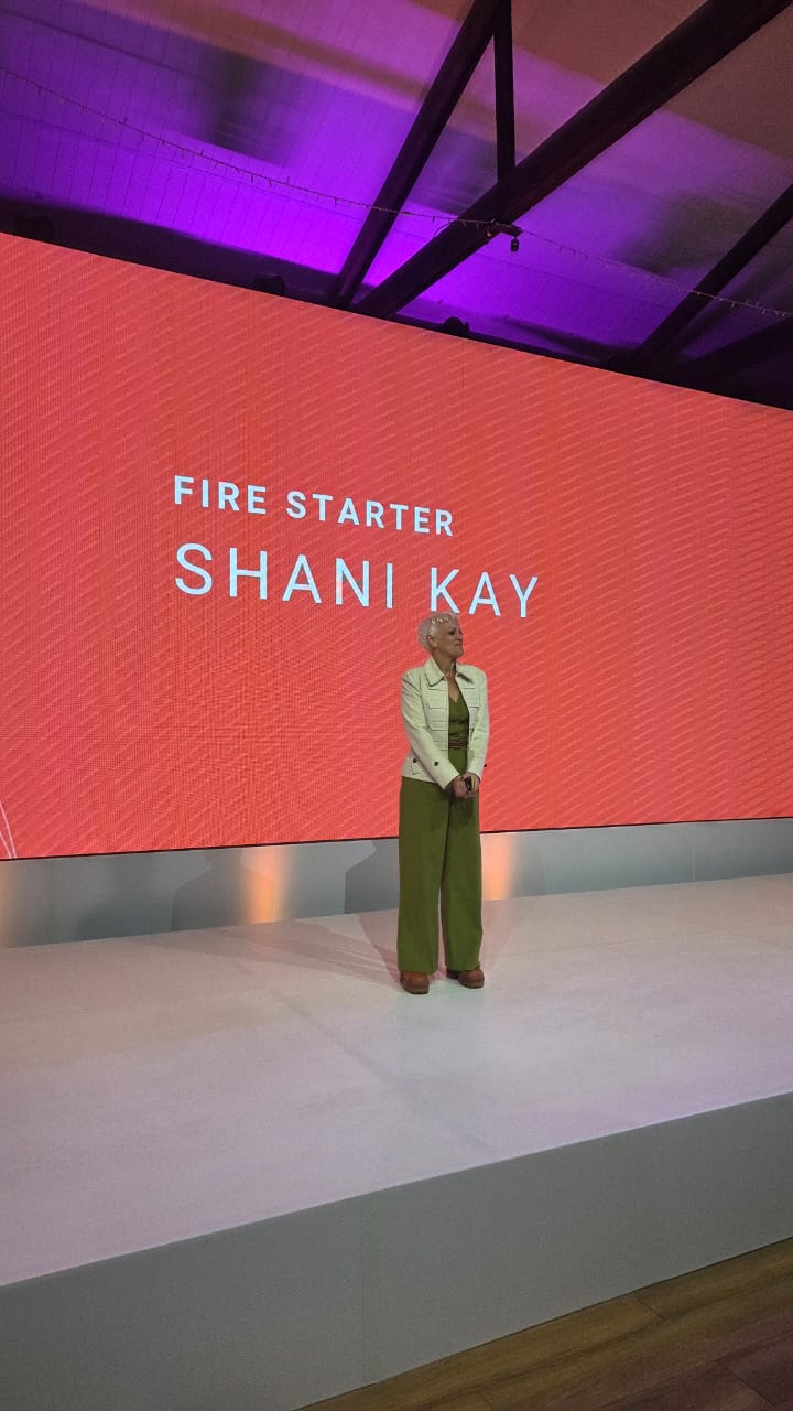 Shani Kay on stage delivering a keynote presentation-actions
